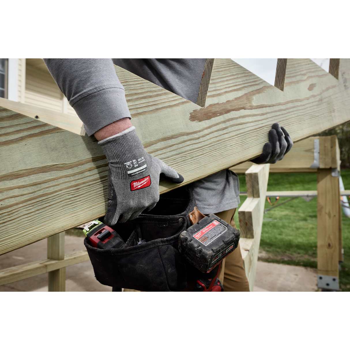 Worker lifting a wooden board wearing Milwaukee Cut Level 4 High Dexterity gloves