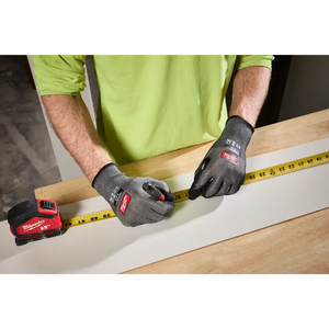 Person measuring wood wearing Milwaukee Cut Level 3 High Dexterity gloves