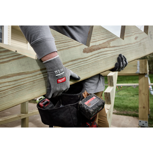 Worker lifting a wooden board wearing Milwaukee Cut Level 4 High Dexterity gloves